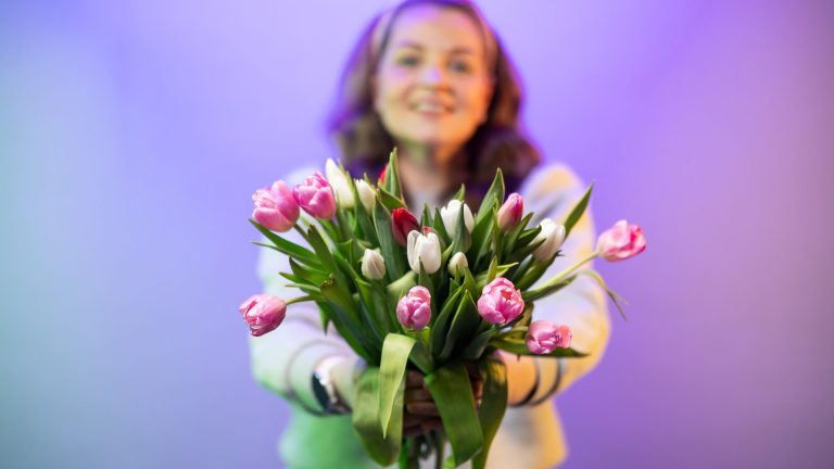 Henkilö ojentaa tulppaanikimpun.